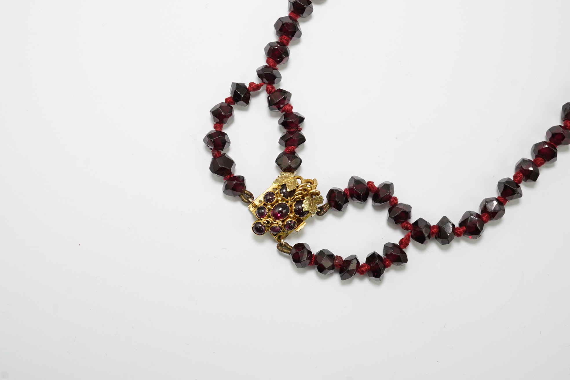 A Victorian facet cut garnet necklace, with cabochon garnet cluster set gold clasp